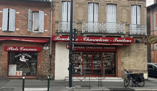 Façade de deux magasins français en brique avec auvents rouges, un vélo sur le trottoir à Toulouse en Haute-Garonne 31