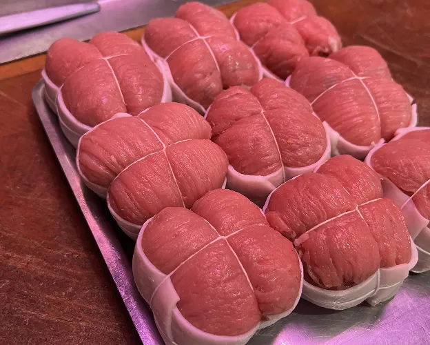 Préparations de viande rose ficelées dans des barquettes blanches sur un plateau métallique à Toulouse en Haute-Garonne 31