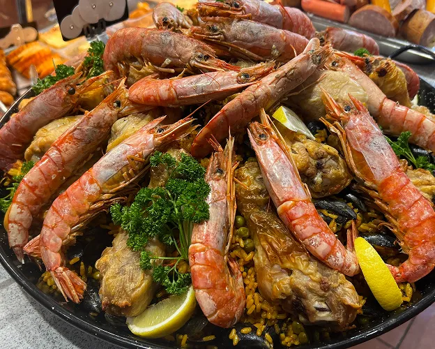 Grande paella avec crevettes, poulet et moules, garnie de persil et citron à Toulouse en Haute-Garonne 31